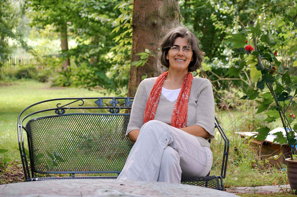 Elisabeth Goebel-Krayer sitzt auf einer Bank in der Natur.